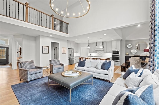 12745 N Larkspur Ln, Platte City, MO 64079 - living room with stairway, light wood-style flooring, a high ceiling, a notable chandelier, and recessed lighting