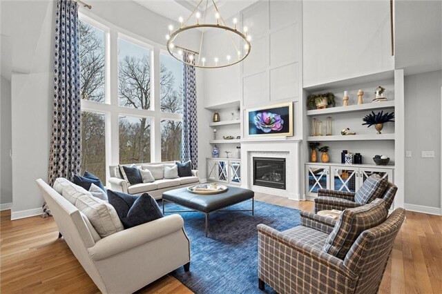12745 N Larkspur Ln, Platte City, MO 64079 - living room featuring a high ceiling, wood finished floors, a chandelier, and baseboards