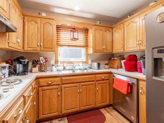 kitchen featuring a sink, light countertops, light wood-style floors, under cabinet range hood, and appliances with stainless steel finishes