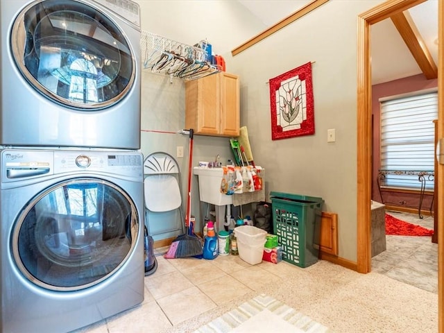 washroom with stacked washer / drying machine, cabinet space, baseboards, and tile patterned flooring