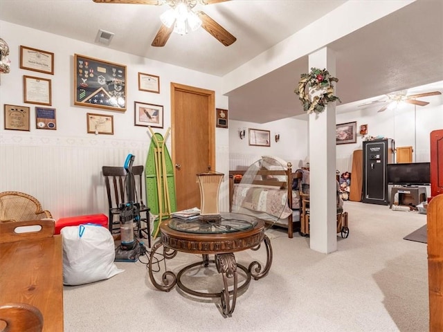 sitting room featuring carpet flooring, visible vents, wainscoting, and ceiling fan