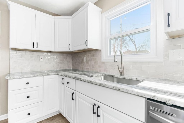 kitchen with decorative backsplash, white cabinetry, and a sink