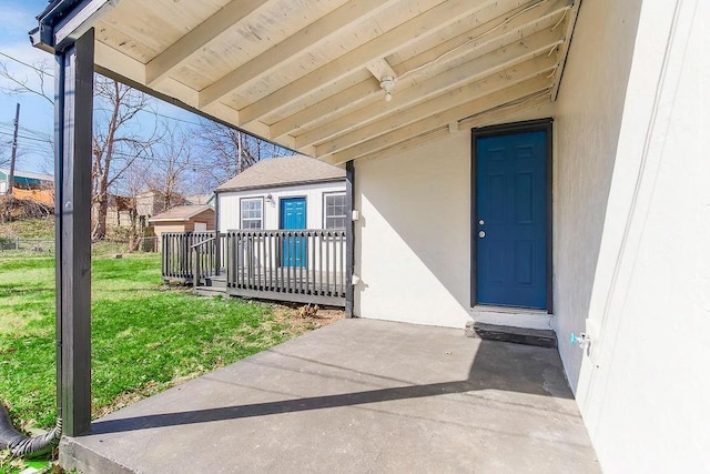 view of exterior entry with stucco siding and a yard