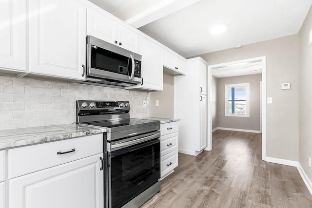 kitchen with light stone countertops, baseboards, light wood finished floors, decorative backsplash, and appliances with stainless steel finishes