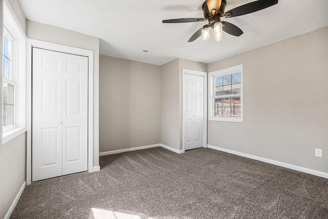 unfurnished bedroom featuring carpet flooring, ceiling fan, baseboards, and multiple closets