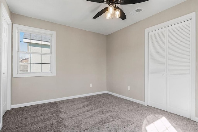 unfurnished bedroom featuring visible vents, a closet, carpet, baseboards, and ceiling fan