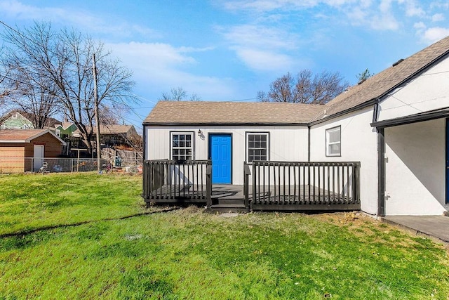 exterior space featuring a yard, roof with shingles, a wooden deck, and fence