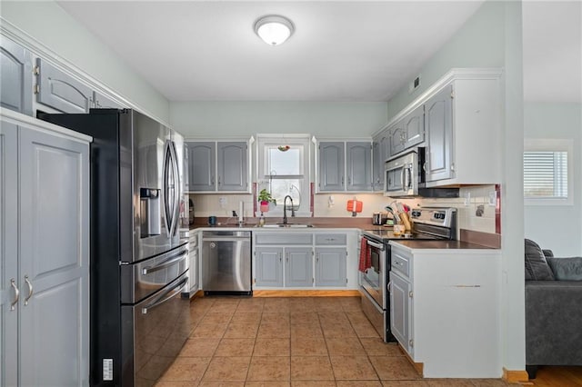 kitchen featuring a sink, appliances with stainless steel finishes, gray cabinetry, and light tile patterned floors