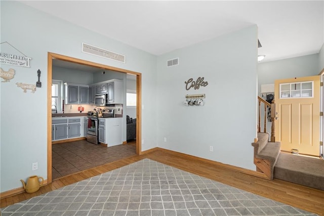 living room with visible vents, stairs, baseboards, and wood finished floors