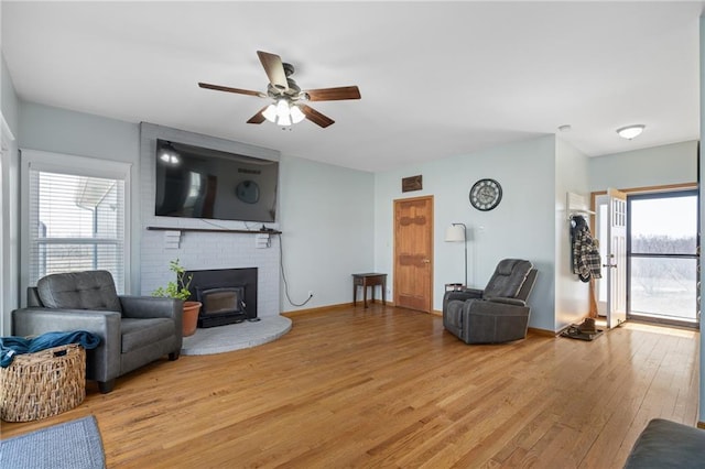 living area with light wood-type flooring, plenty of natural light, baseboards, and a ceiling fan