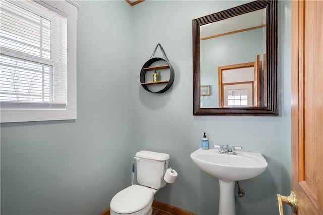 half bathroom with toilet, baseboards, and a sink