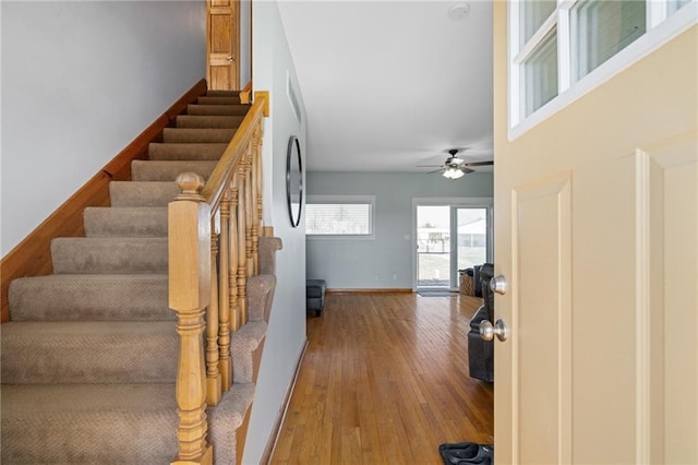 staircase with baseboards, ceiling fan, and wood finished floors