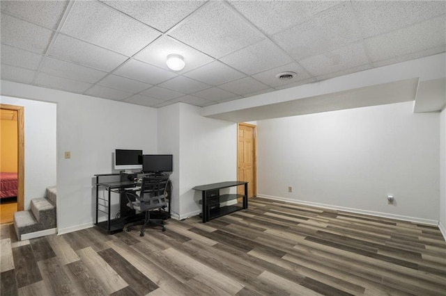 office space with visible vents, a drop ceiling, baseboards, and wood finished floors