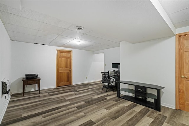 interior space featuring a paneled ceiling, visible vents, heating unit, and wood finished floors