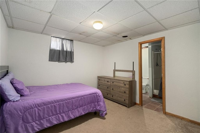 bedroom featuring a drop ceiling, carpet flooring, ensuite bath, and baseboards