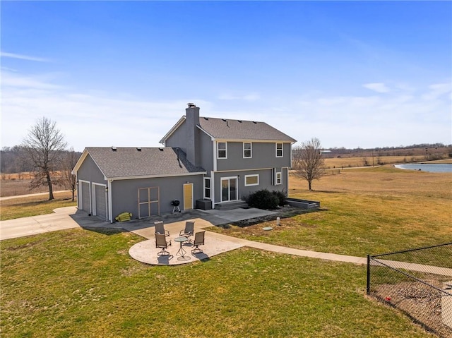 back of property featuring stucco siding, a lawn, concrete driveway, a chimney, and a patio area