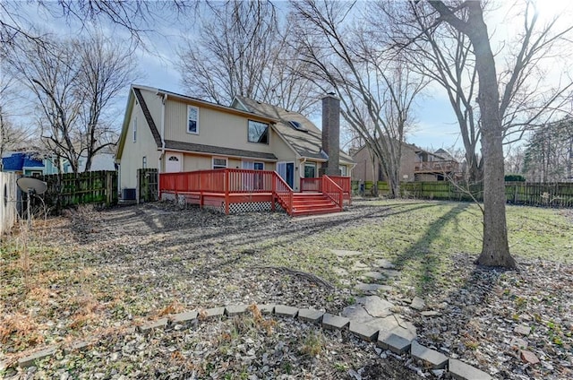 rear view of house featuring a deck, a yard, a fenced backyard, and a chimney