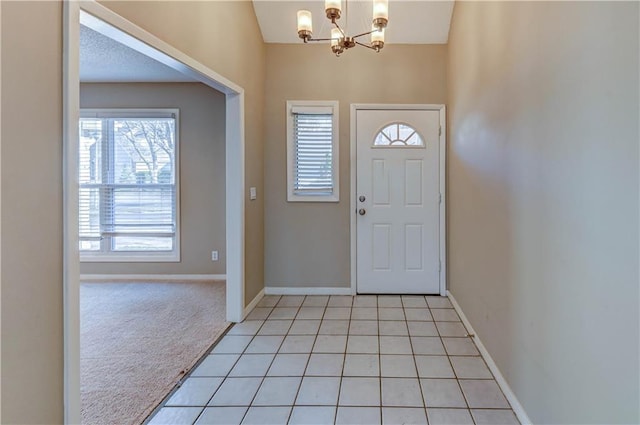 entryway featuring light carpet, light tile patterned flooring, baseboards, and a chandelier