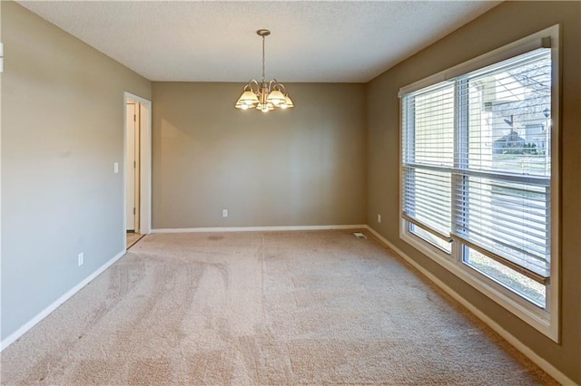 carpeted empty room featuring a notable chandelier, baseboards, and a textured ceiling