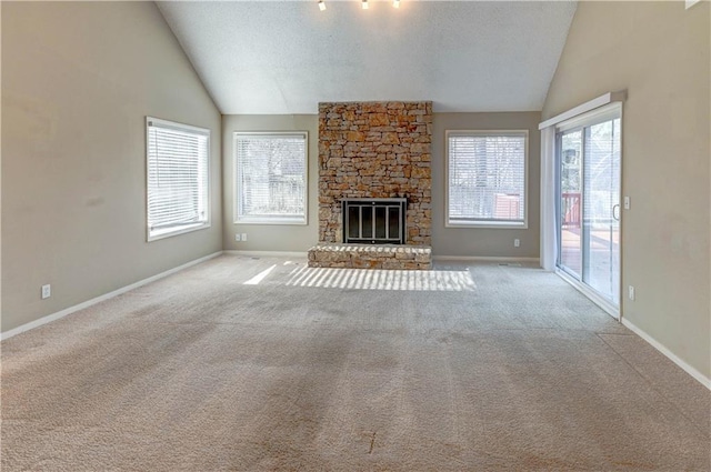 unfurnished living room featuring baseboards, carpet floors, lofted ceiling, a stone fireplace, and a textured ceiling