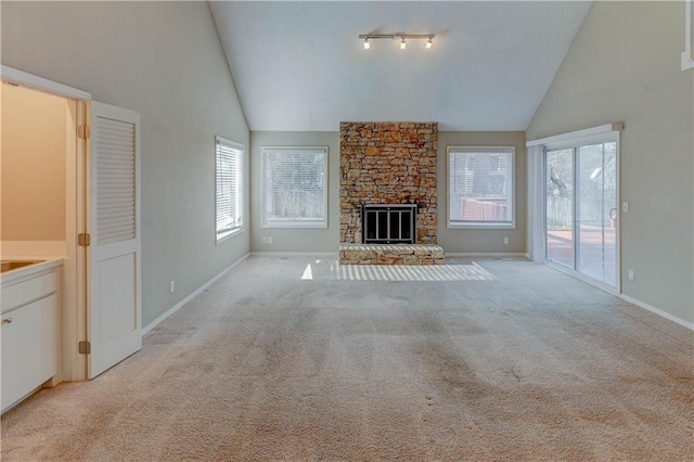 unfurnished living room featuring a stone fireplace, high vaulted ceiling, baseboards, and light carpet