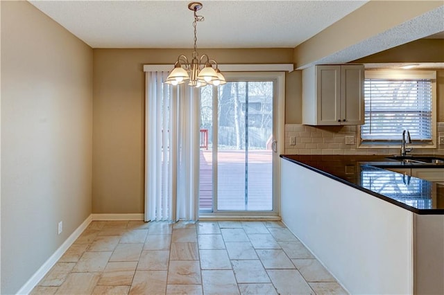 kitchen with dark countertops, plenty of natural light, a chandelier, and a sink