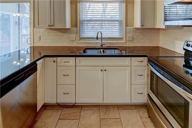 kitchen with tasteful backsplash, white cabinets, appliances with stainless steel finishes, and a sink