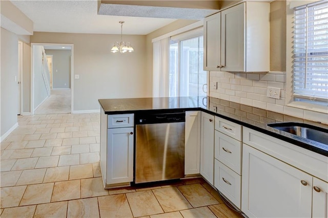 kitchen with dark countertops, dishwasher, a peninsula, and an inviting chandelier