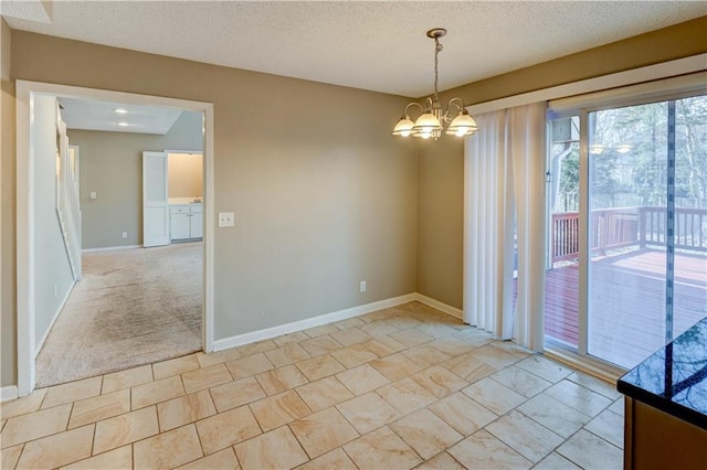 unfurnished room featuring light carpet, a notable chandelier, baseboards, and a textured ceiling