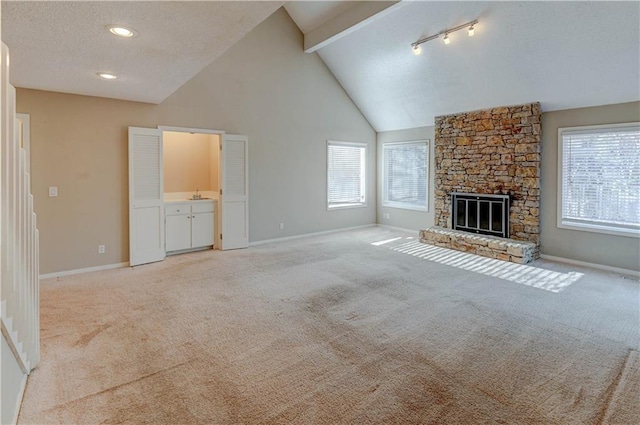 unfurnished living room with light colored carpet, baseboards, and a textured ceiling