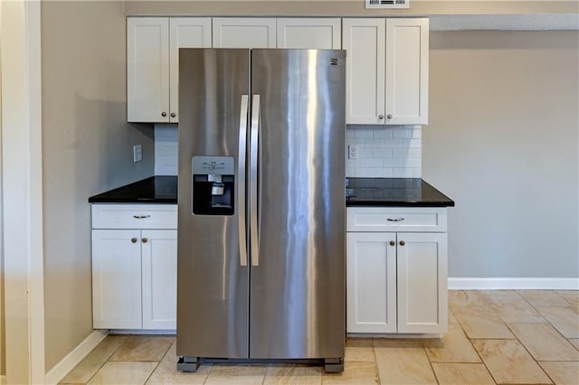 kitchen with visible vents, stainless steel fridge with ice dispenser, white cabinetry, dark countertops, and tasteful backsplash