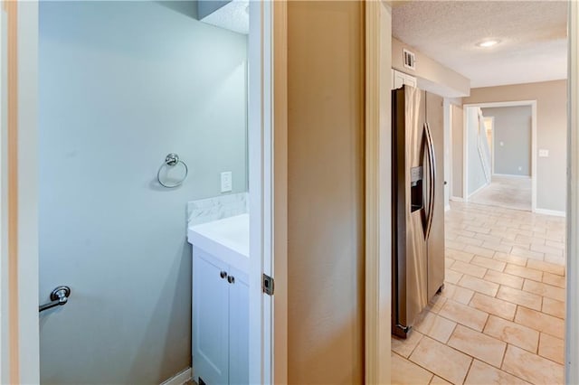 bathroom with visible vents, a textured ceiling, tile patterned flooring, baseboards, and vanity