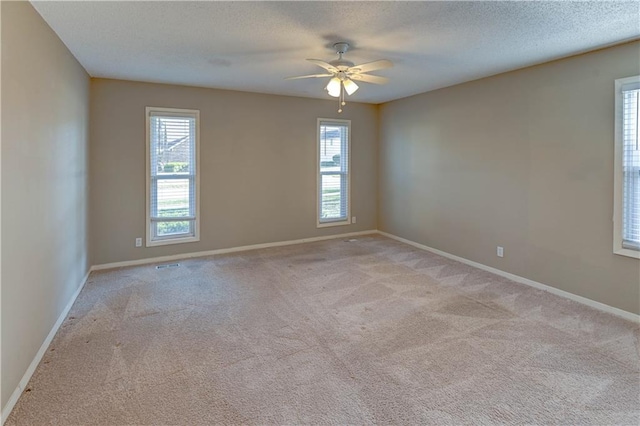 empty room featuring baseboards, plenty of natural light, light colored carpet, and a ceiling fan