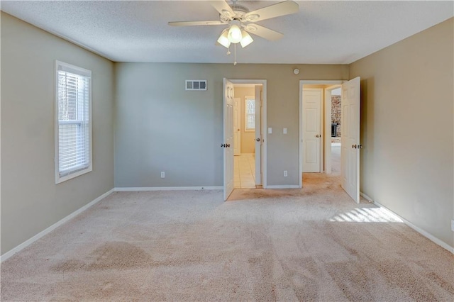 unfurnished bedroom with visible vents, a textured ceiling, carpet, baseboards, and ceiling fan