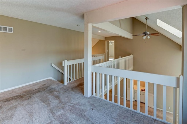 staircase featuring visible vents, carpet, lofted ceiling with skylight, a textured ceiling, and a ceiling fan