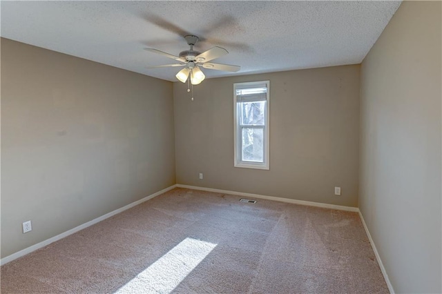 empty room featuring visible vents, a ceiling fan, a textured ceiling, carpet floors, and baseboards