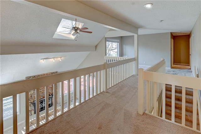 corridor with lofted ceiling with skylight, carpet, and a textured ceiling