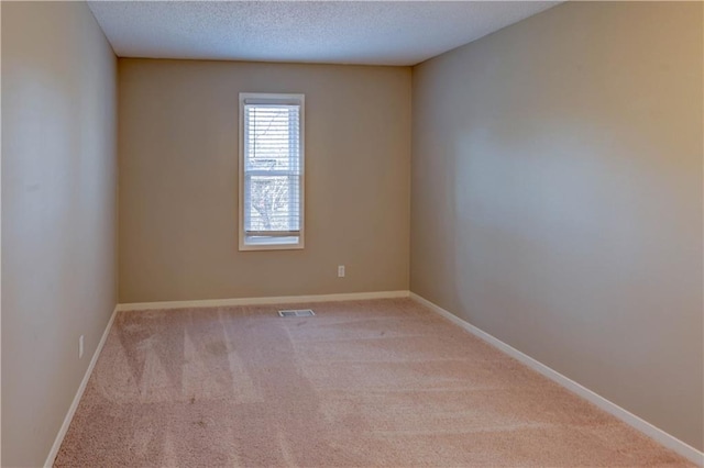 unfurnished room with visible vents, a textured ceiling, carpet, and baseboards