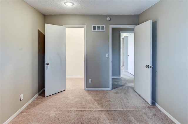 unfurnished bedroom with visible vents, baseboards, a textured ceiling, and carpet flooring