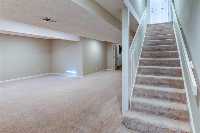 stairway featuring visible vents, carpet floors, a textured ceiling, and baseboards