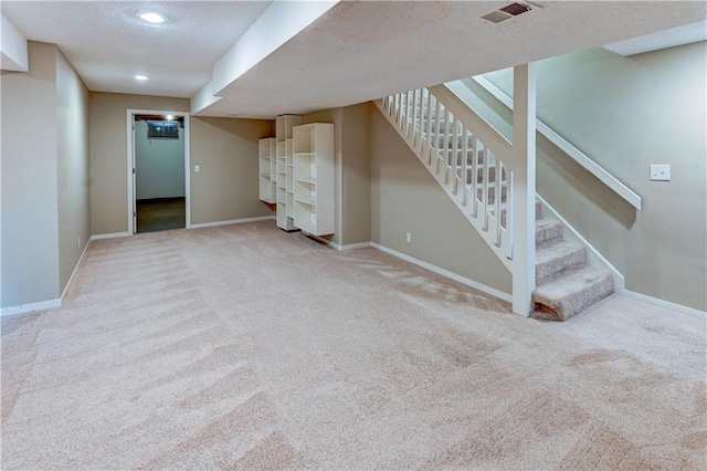 finished basement featuring stairway, baseboards, visible vents, carpet floors, and a textured ceiling