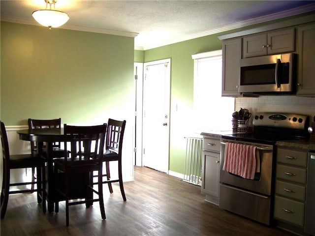 dining space featuring a textured ceiling, dark wood-type flooring, baseboards, and ornamental molding