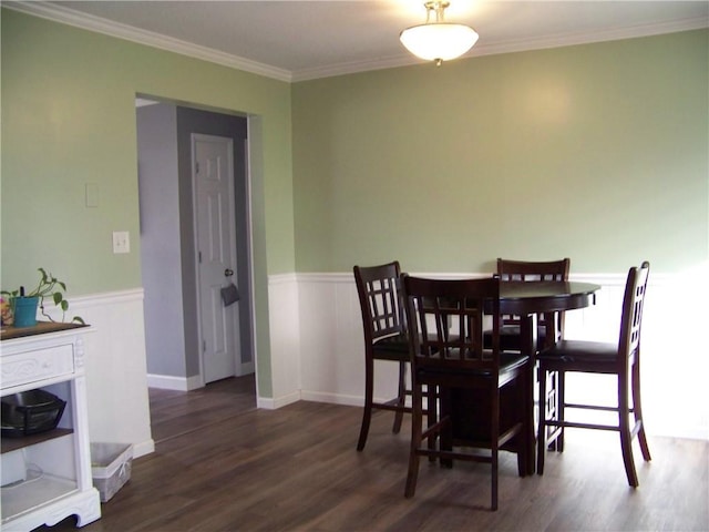 dining room with wood finished floors, wainscoting, and crown molding