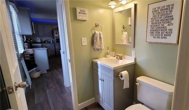 bathroom with baseboards, toilet, wood finished floors, and vanity