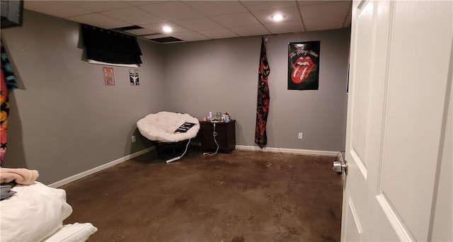 living area with a paneled ceiling, baseboards, and concrete flooring