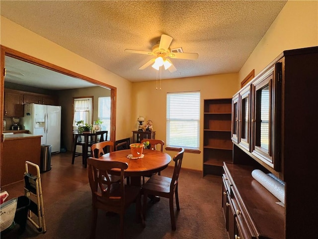 dining room with dark colored carpet, baseboards, a textured ceiling, and a ceiling fan