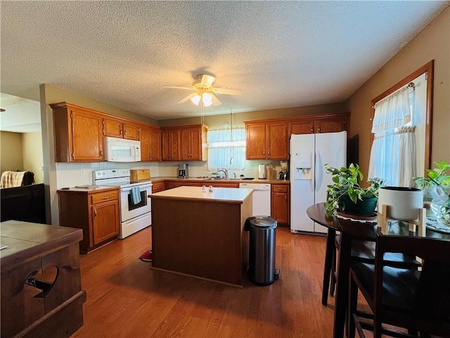 kitchen featuring white appliances, a ceiling fan, dark wood-type flooring, and a sink