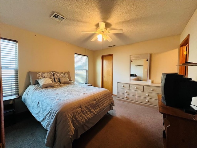 carpeted bedroom featuring ceiling fan, visible vents, and a textured ceiling