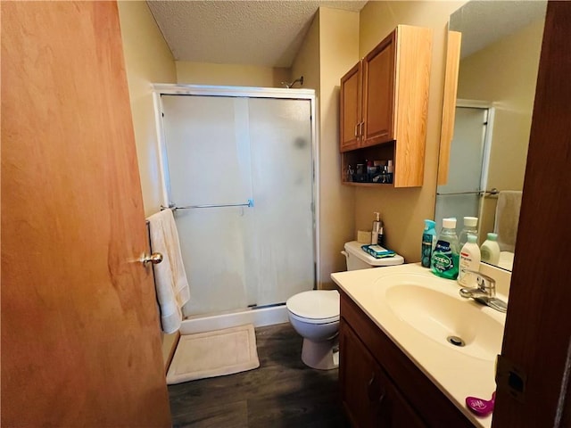 full bath with vanity, wood finished floors, a stall shower, a textured ceiling, and toilet