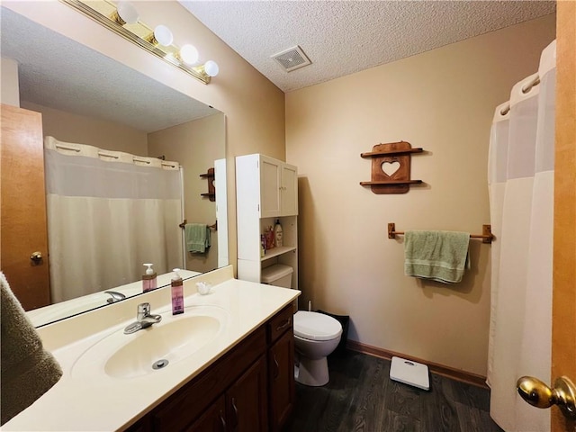 bathroom featuring visible vents, baseboards, toilet, wood finished floors, and a textured ceiling